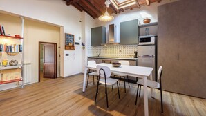 A modern kitchen with white cabinetry, a microwave, and a dining area with a white table and chairs. - Una Finestra sulle Cappelle Medicee by Mmega (Florence)