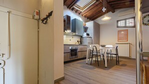 A kitchen with wooden flooring, a dining area with white chairs, and a built-in oven. - Una Finestra sulle Cappelle Medicee by Mmega (Florence)