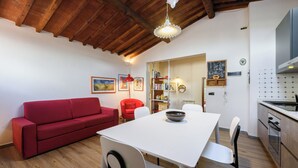 A modern kitchen with white cabinets, a built-in oven, and a dining area with a white table and chairs. - Una Finestra sulle Cappelle Medicee by Mmega (Florence)