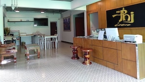 A reception area with a wooden counter, a television mounted on the wall, and a seating area with chairs and tables.