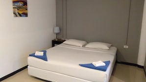 A hotel room with a bed, a nightstand, a lamp, and a painting on the wall.