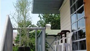 A modern building with a flat roof, a potted plant, and a set of white plastic chairs outside.