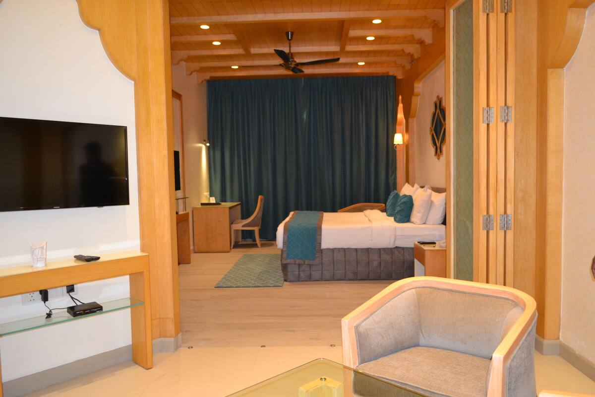 A hotel room with a bed, a TV, a chair, and a desk.