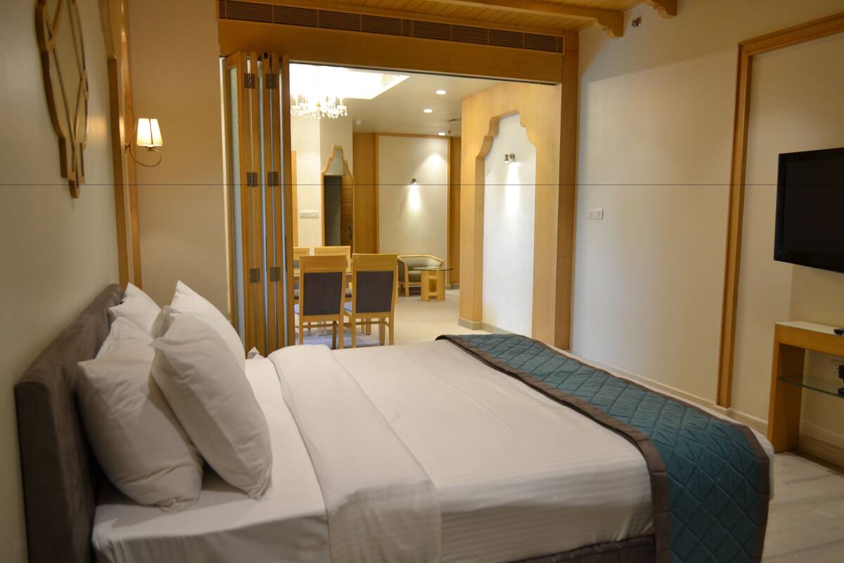A hotel room with a bed, a TV, a desk, and a chair.