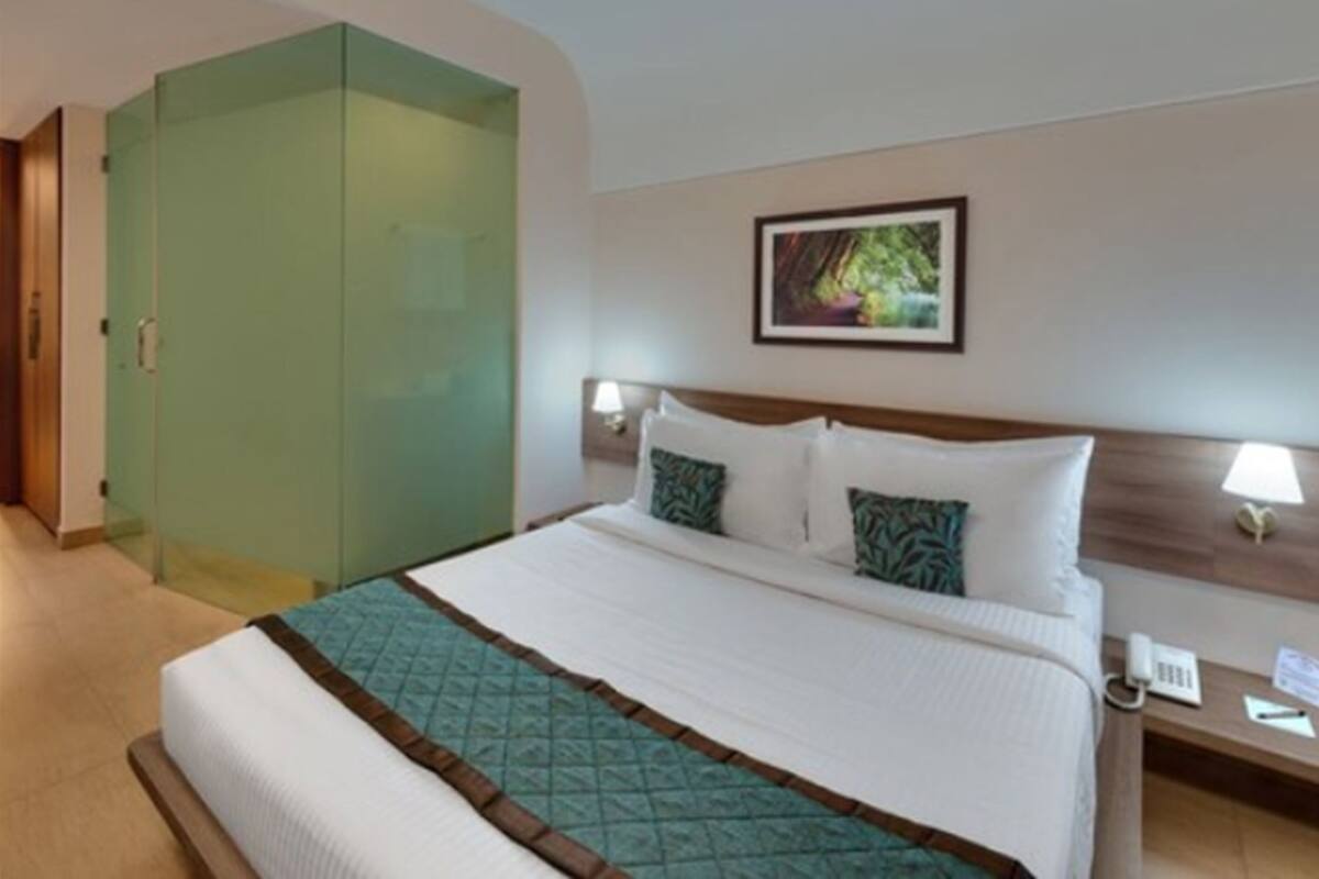 A hotel room with a bed, a nightstand, a phone, and a picture on the wall.
