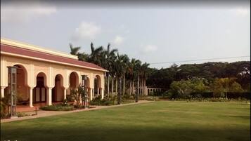 A building with a red roof and multiple arches, surrounded by a well-maintained lawn and palm trees.
