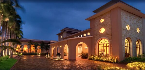 A hotel with a stone facade, arched walkways, and warm lighting. - Ibiza The Fern Resort and Spa Kolkata (Alipur)
