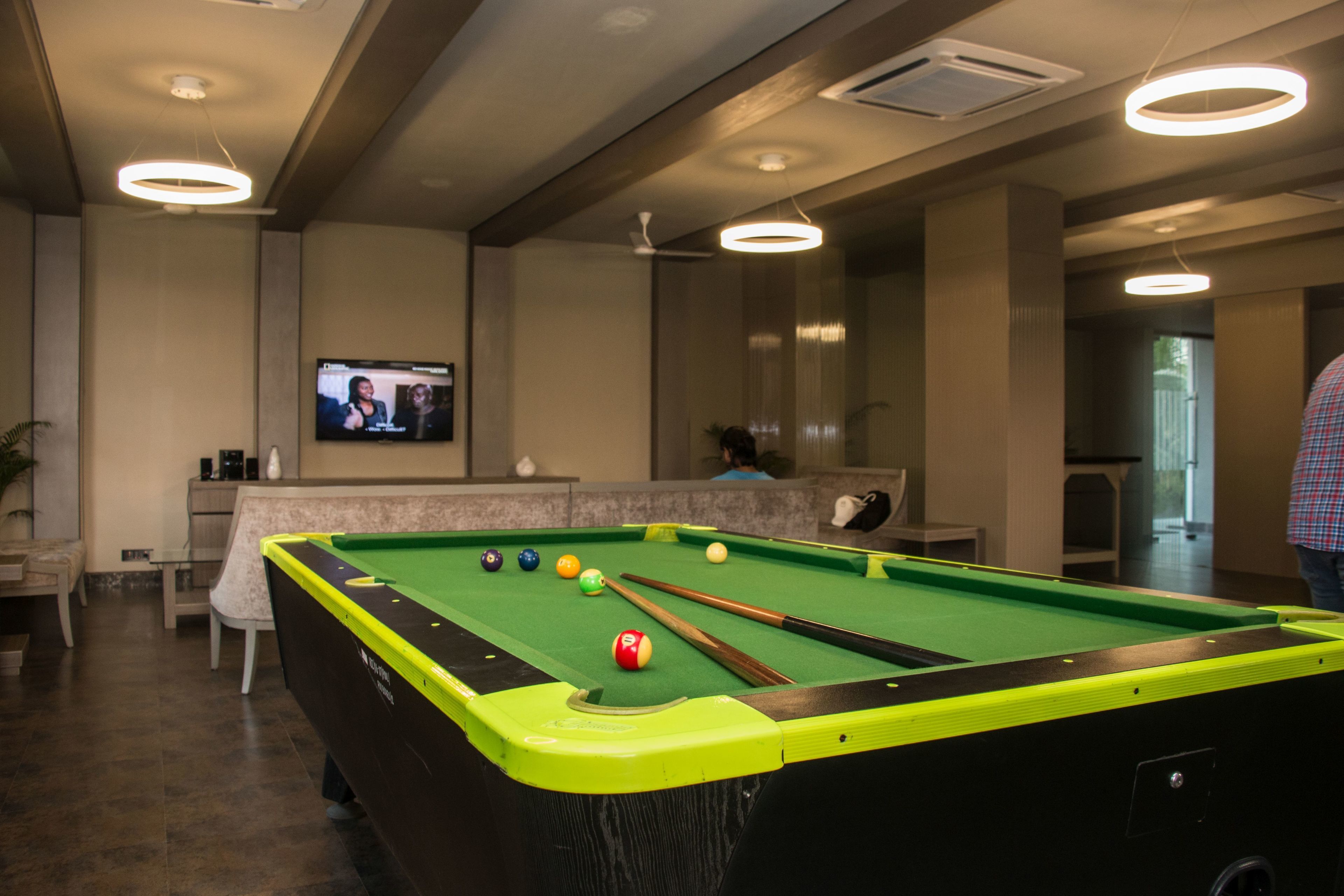 Une table de billard avec des billes, un écran de télévision et un coin bar.