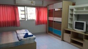 A bedroom with a bed, a TV, a wardrobe, and a window with curtains. - Popular Condo Muangthong Thani (Pak Kret)