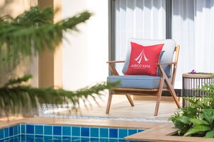 Una silla de descanso con cojín, cerca de una piscina, con la etiqueta 'AURICO KATA RESORT & SPA'.