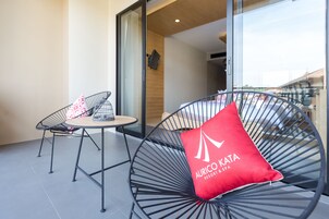 En balkon med to stole, hvoraf den ene har en rød pude og den anden en stribet pude.