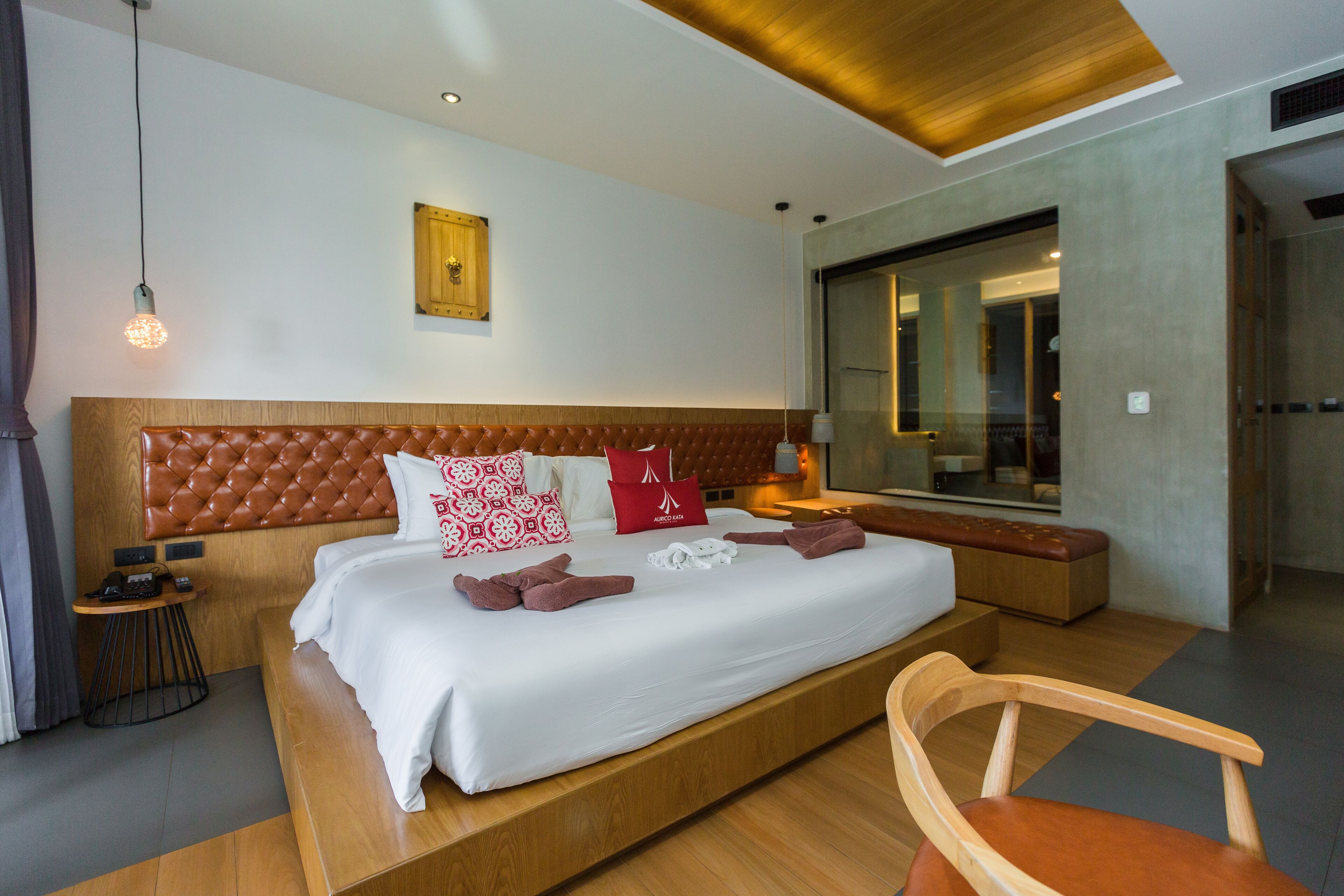 A modern hotel room with a large bed, wooden headboard, and a wooden bench.