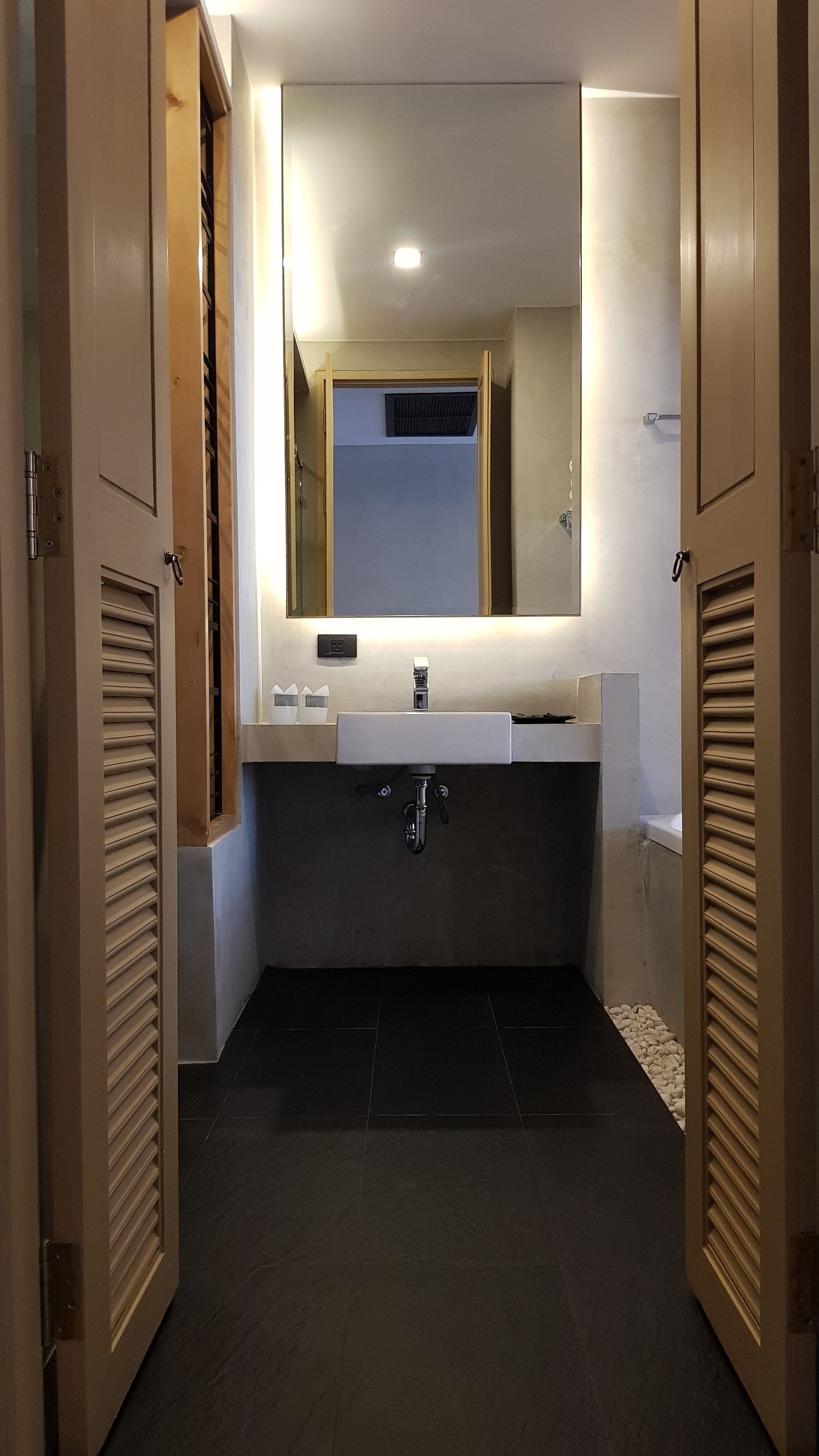 A bathroom with a white sink, a mirror above it, and a shower area visible through a door.