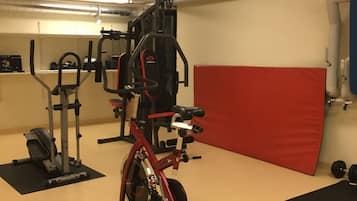 Un gimnasio con equipo de ejercicio, incluyendo una bicicleta estática, una cinta de correr y máquinas de pesas.