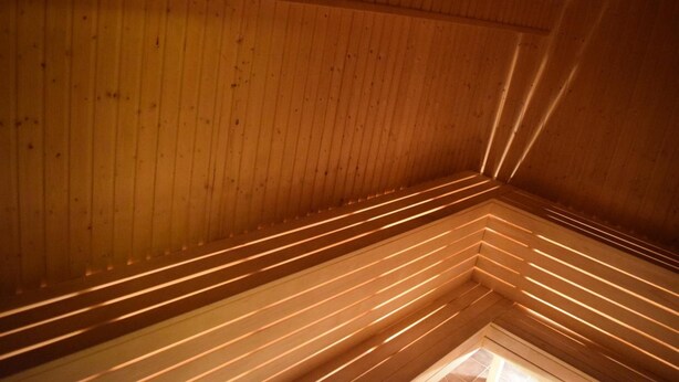 A wooden interior with slatted ceiling design and a visible skylight.
