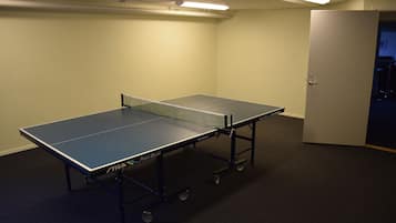 A ping pong table in a room with a door and carpeted floor.