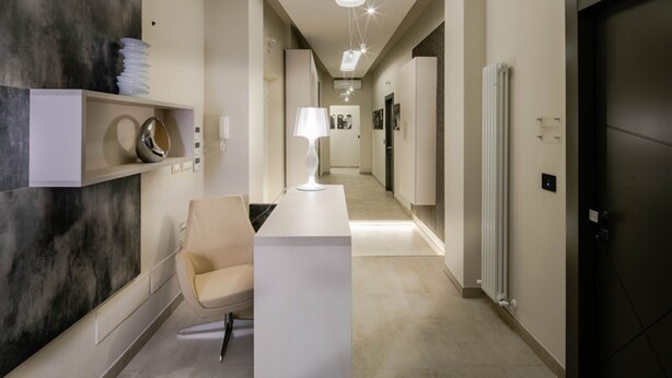 A modern hotel lobby with a reception desk, a seating area, and a hallway leading to other rooms. - Via Veneto Luxury Suites (Rome)