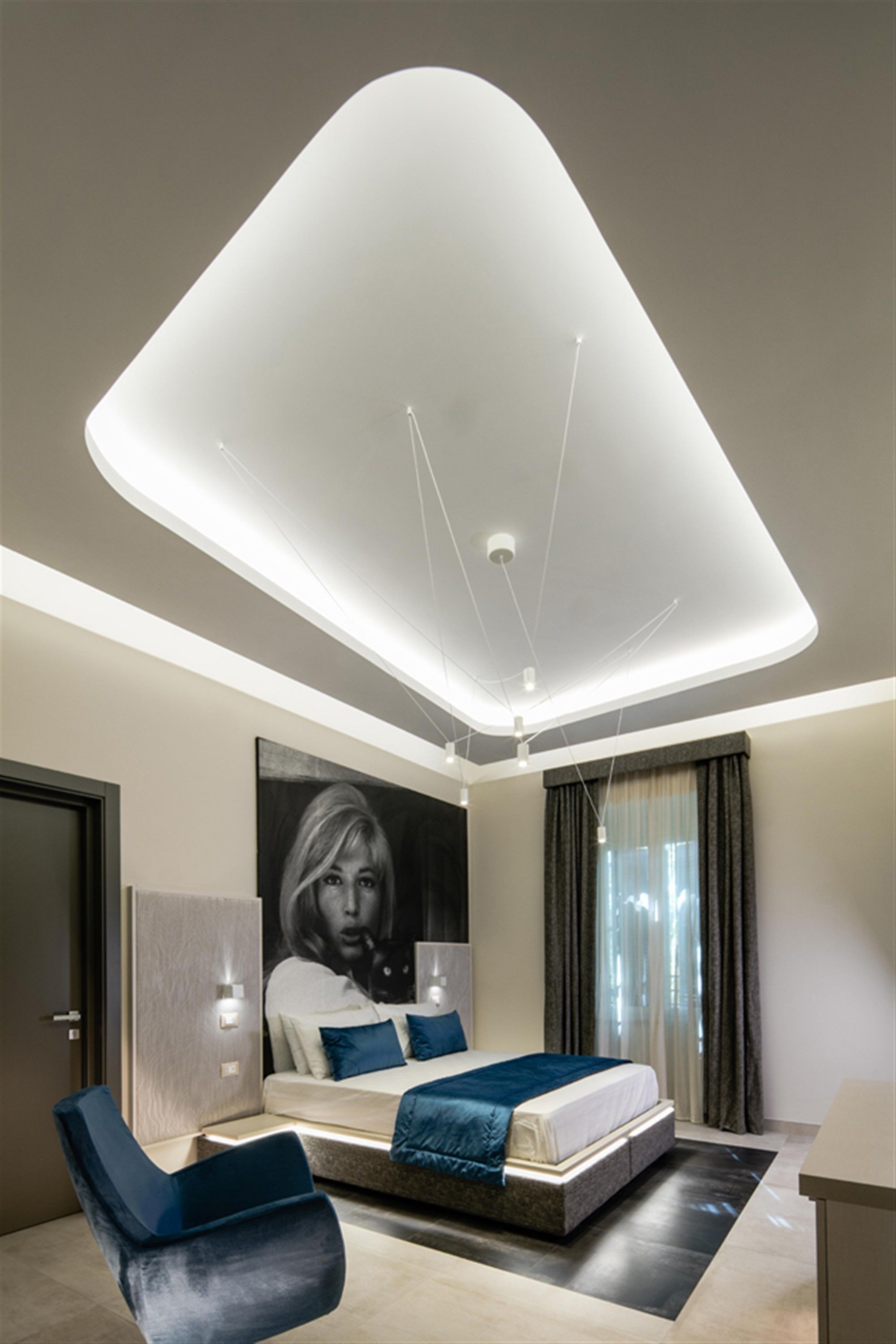 Un dormitorio moderno con una cama, una silla y un cartel grande en la pared.