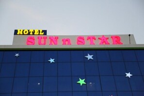 Un letrero de hotel con el nombre 'SUNn STAR' en letras rosadas brillantes sobre un fondo azul.