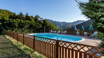 Relax by the serene oval-shaped pool surrounded by lush greenery and mountains.