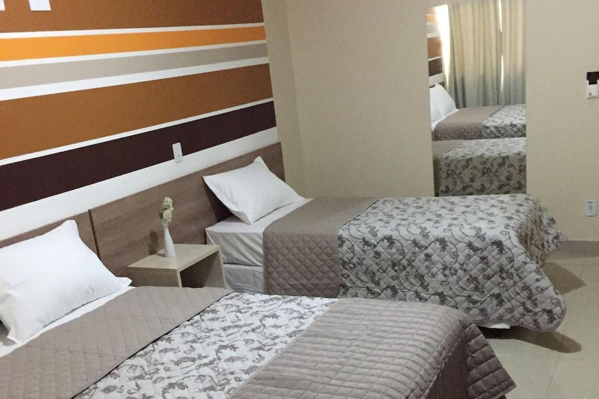 Habitación de hotel con dos camas, un cabecero a rayas, una mesita de noche y un espejo.