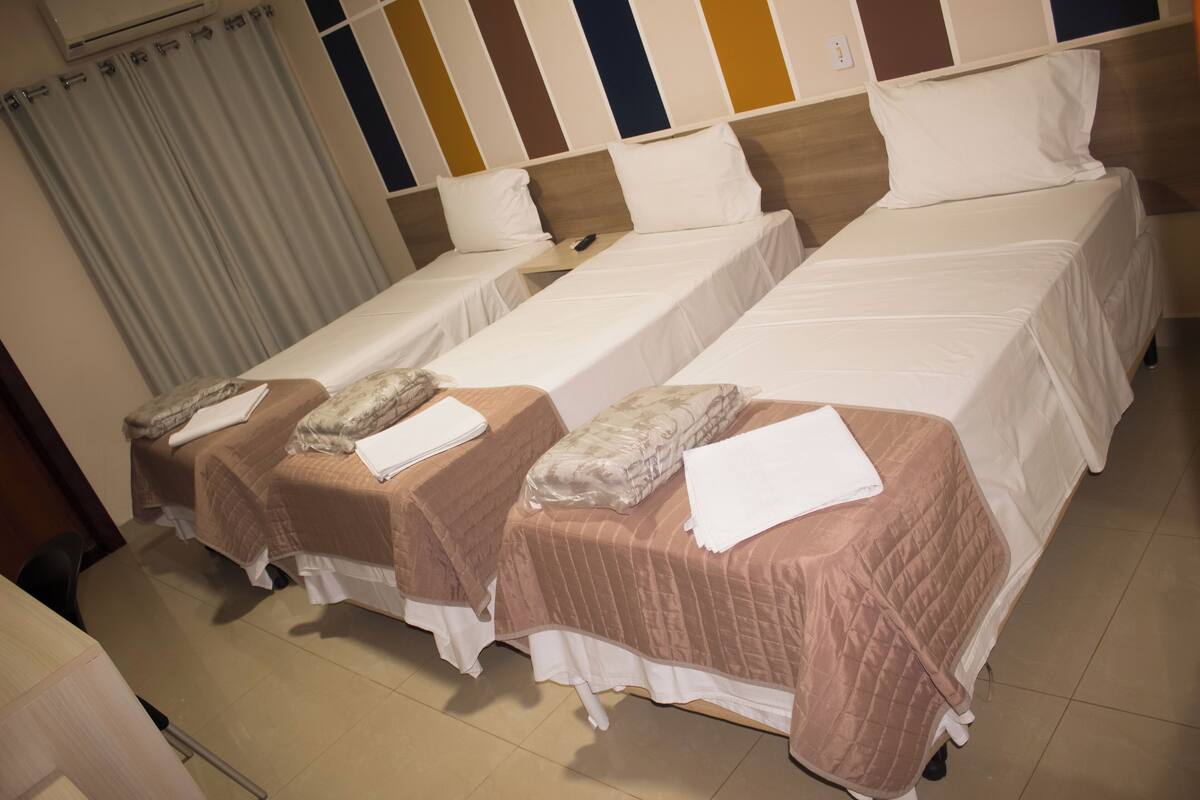 A hotel room with two single beds, each with a pillow and a blanket.