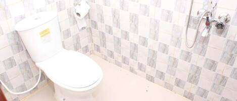 Un baño con inodoro, ducha y pared con azulejos.
