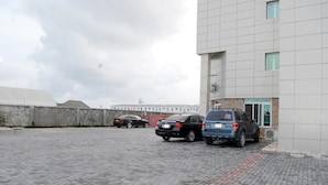 Uma área de estacionamento com dois carros estacionados em frente a um edifício com fachada em azulejos.