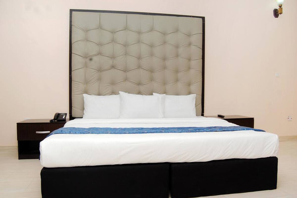 Ein Hotelzimmer mit einem großen Bett, einem Kopfteil, einem Nachttisch mit Telefon und einem Beistelltisch.