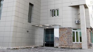 Um edifício moderno com fachada em azulejos, várias janelas e área de entrada pavimentada.