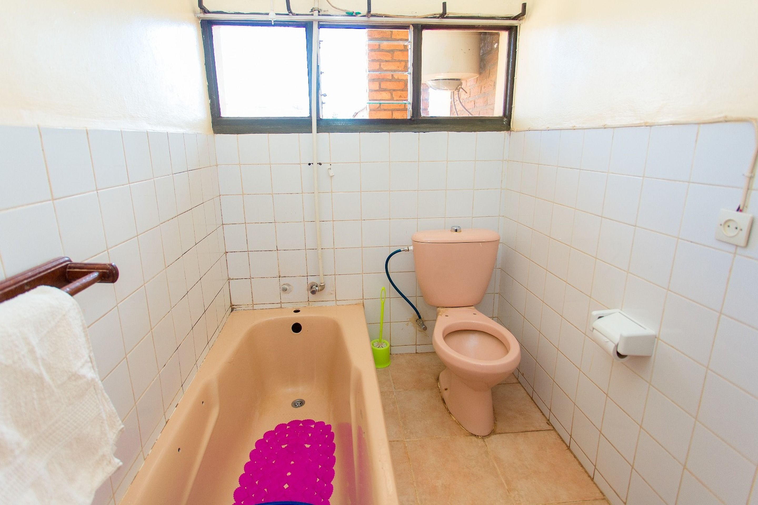Ein Badezimmer mit Badewanne, Toilette und einem Fenster über der Toilette.