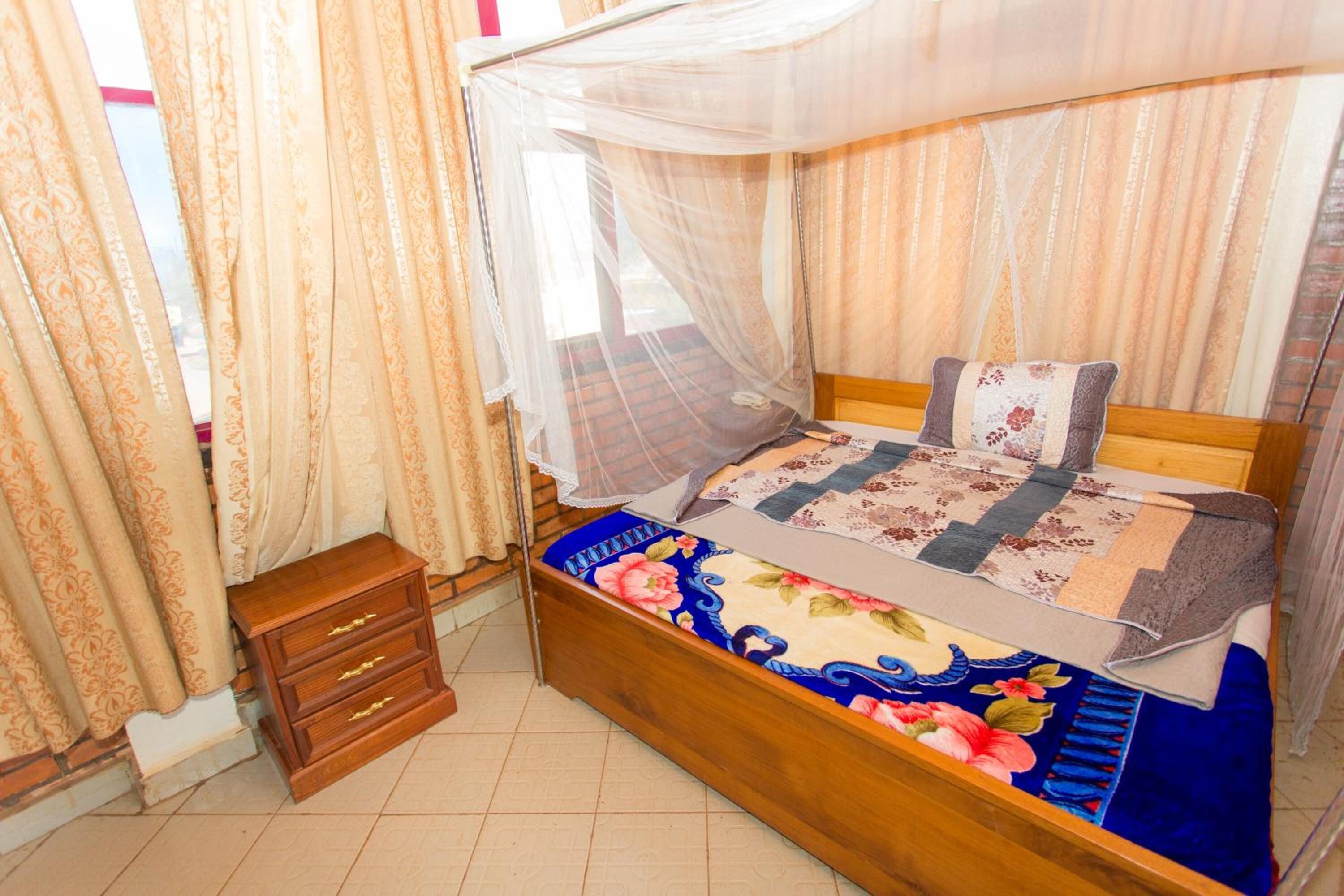 Ein Schlafzimmer mit einem hölzernen Bett, einem Moskitonetz und einem Nachttisch.