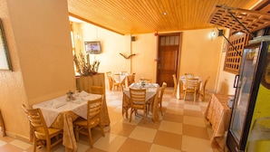 Un comedor con varias mesas y sillas, techo de madera y suelo de baldosas.