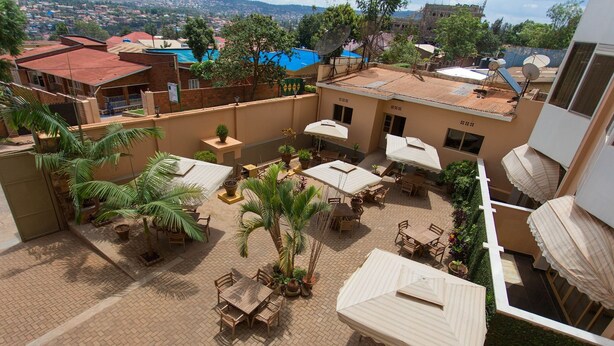 Un patio con varias zonas de estar, palmeras y vistas del barrio circundante.