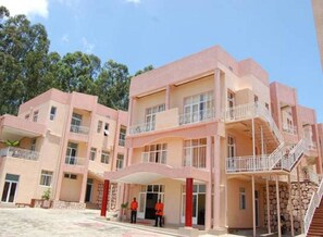 A multi-story hotel with a pink facade, balconies, and a central entrance. - Park View Courts (Kigali)
