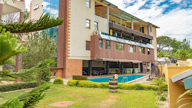 A modern hotel with a pool, outdoor seating, and a well-maintained garden. - Orient Park Hotel (Kigali)