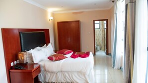 A hotel room with a bed, a nightstand, a wardrobe, and a bathroom visible through an open door. - Orient Park Hotel (Kigali)