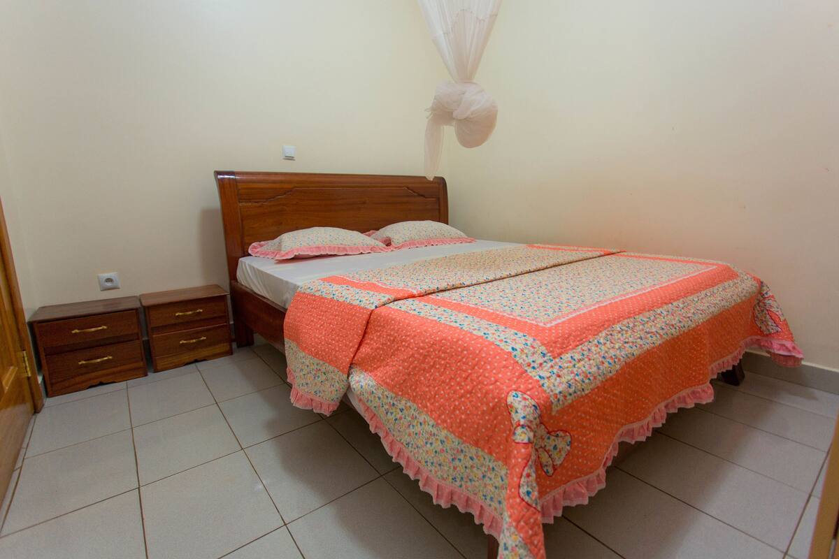 A bedroom with a wooden bed, a nightstand, and a bedside table.