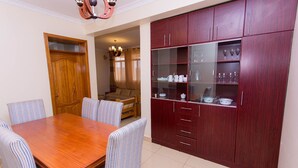 Un comedor con una mesa de madera y sillas a rayas, un aparador de madera con puertas de vidrio y una puerta de madera.