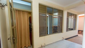 Una habitación con un ventanal grande, una puerta con cortina y suelo de baldosas.