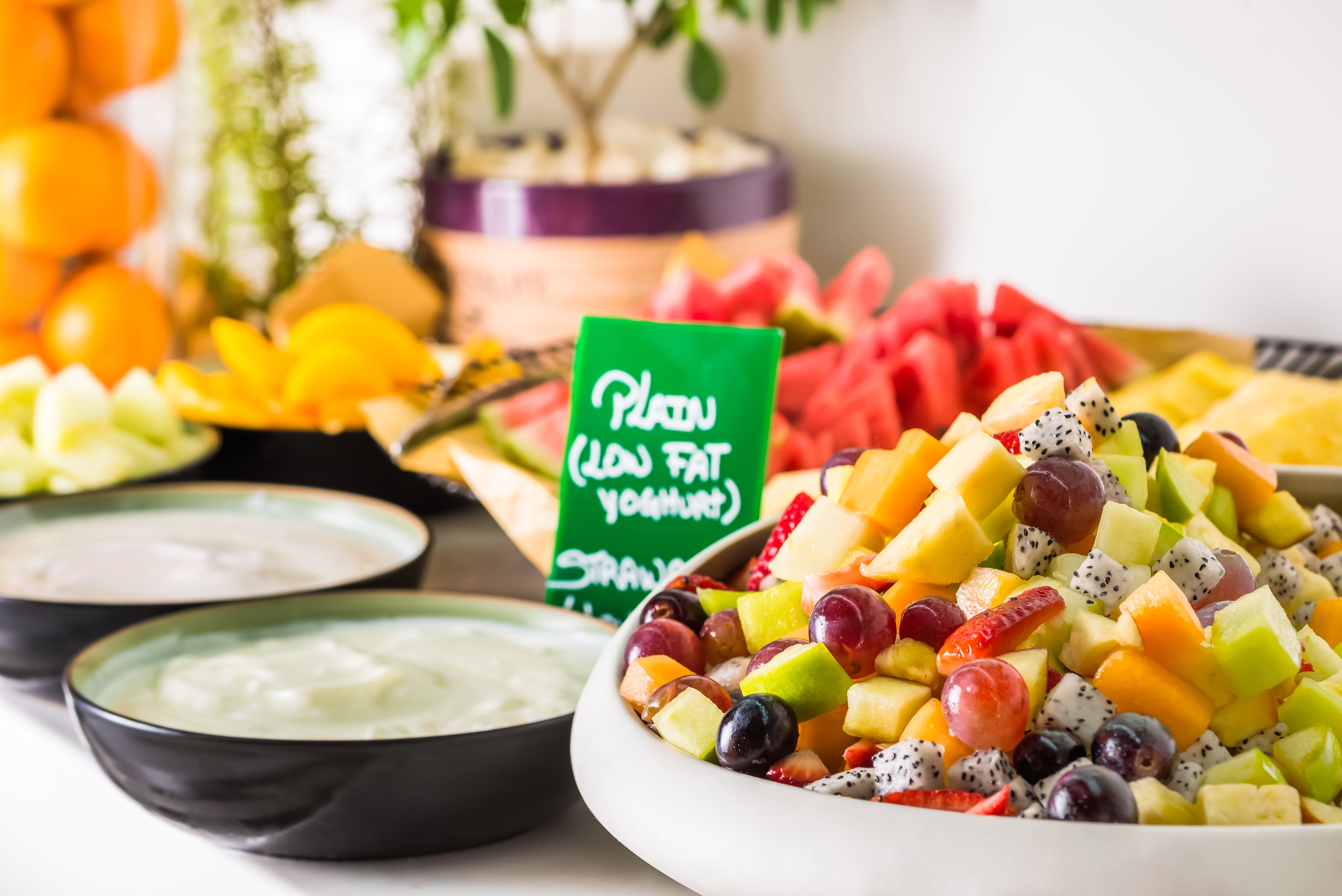 A fruit salad bowl with a sign indicating it is low fat yogurt.