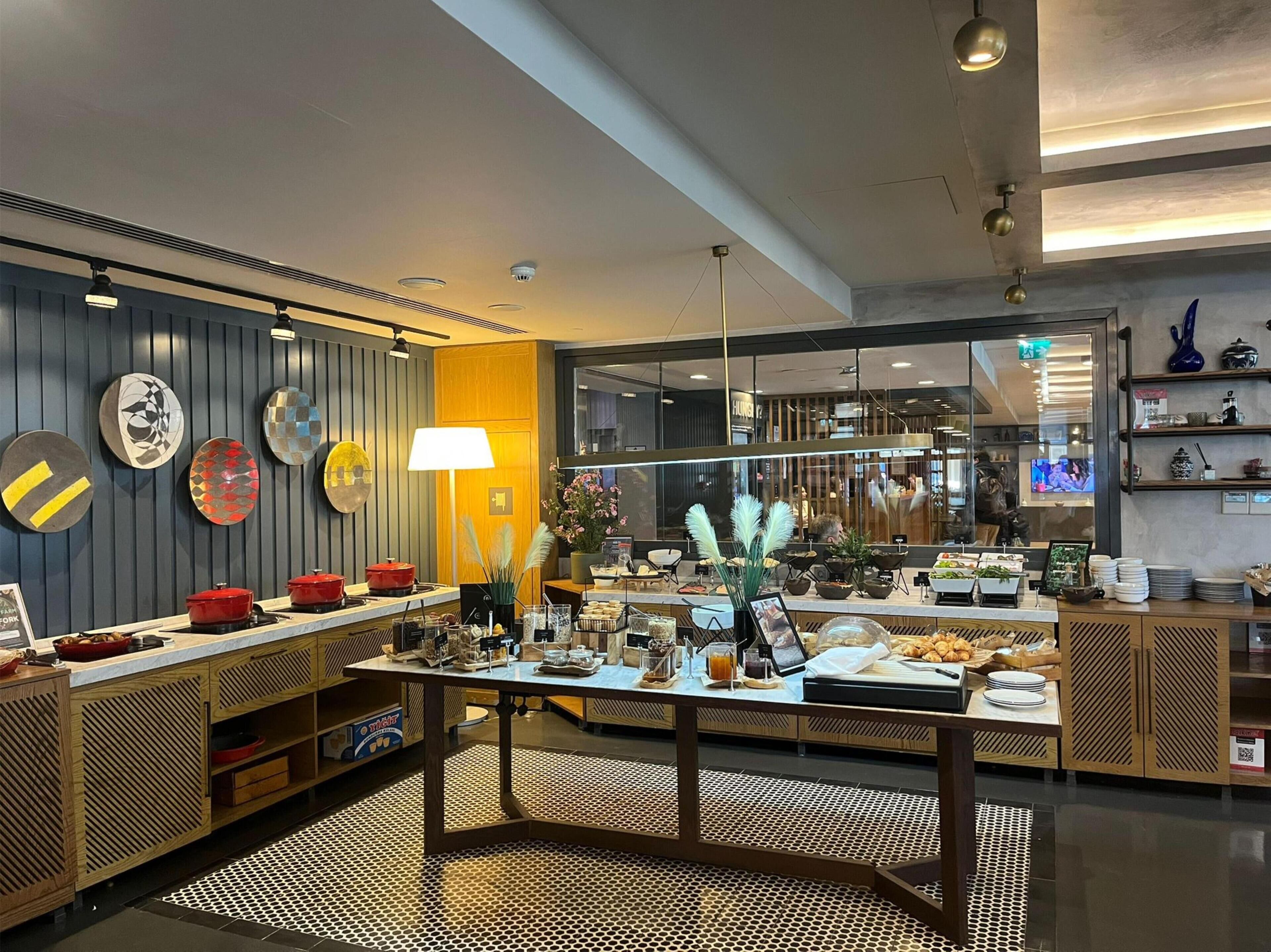 A modern hotel lobby with a reception desk, decorative plates, and a coffee station.