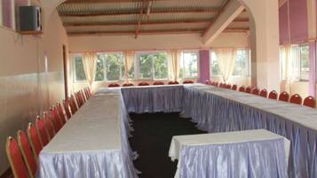 Un salón de conferencias con una mesa larga, sillas rojas y ventanas amplias.