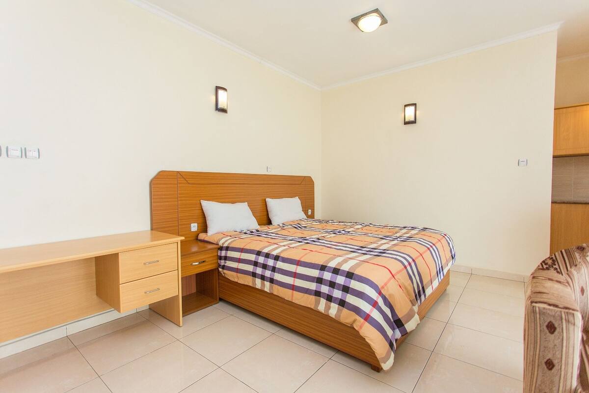 A bedroom with a wooden bed, a desk, and two bedside lamps.