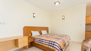 A bedroom with a wooden bed, a desk, and two bedside lamps. - Eden Escape Apartments (Kigali)