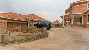 A residential street with houses, a parked SUV, and a paved road. - Eden Escape Apartments (Kigali)