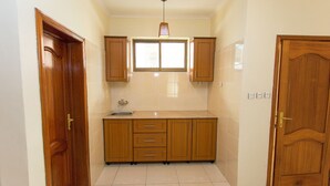 A kitchen with wooden cabinets, a window, and a sink. - Eden Escape Apartments (Kigali)