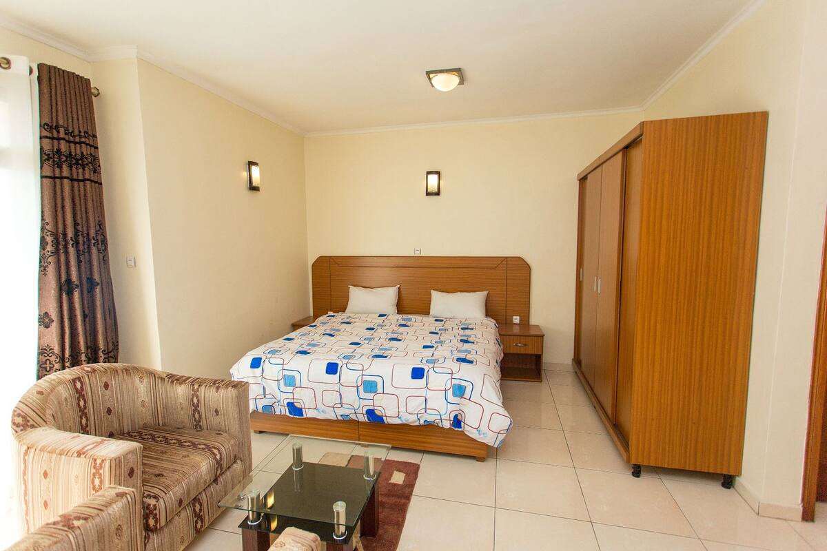 A bedroom with a bed, a sofa, a nightstand, and a wardrobe.