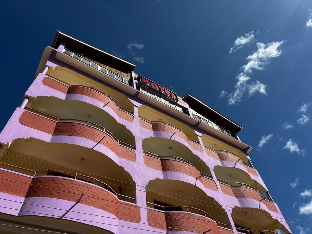 A multi-story hotel with a distinctive architectural design, featuring balconies and a clear sky in the background.