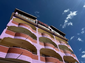 A multi-story hotel with a distinctive architectural design, featuring balconies and a clear sky in the background.